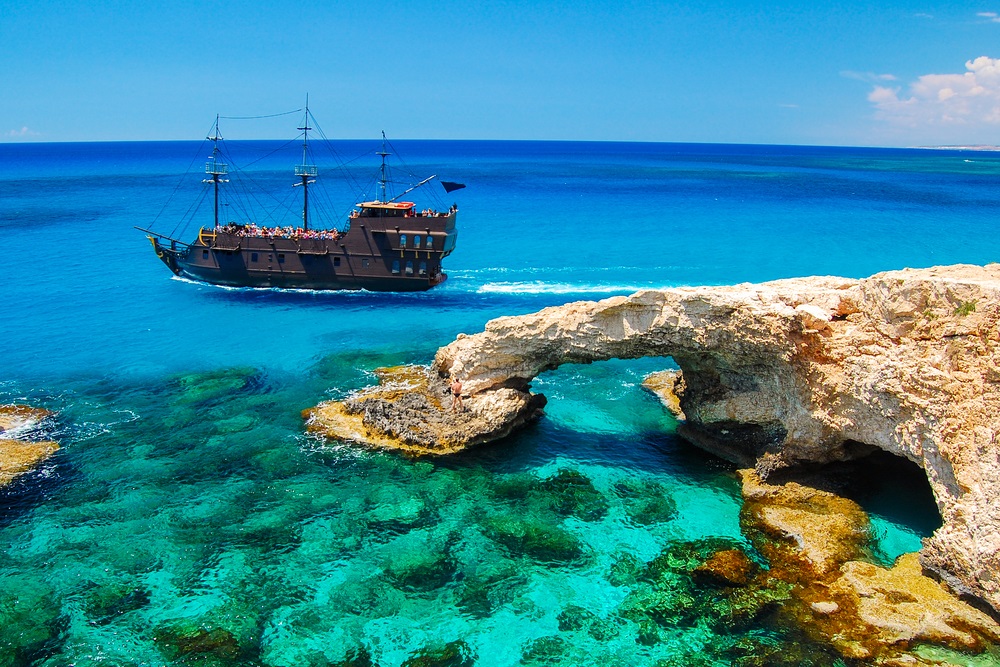 Piracki statek żaglący w pobliżu słynnego łuku skalnego na półwyspie Cavo Greko, Cypr